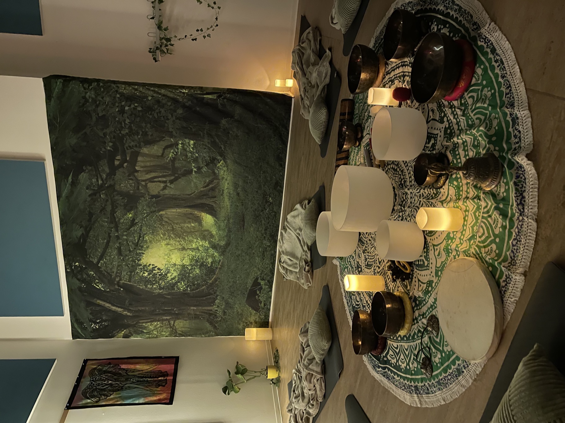 Real photograph of the prepared yoga room with singing bowls, mats and a forest backdrop